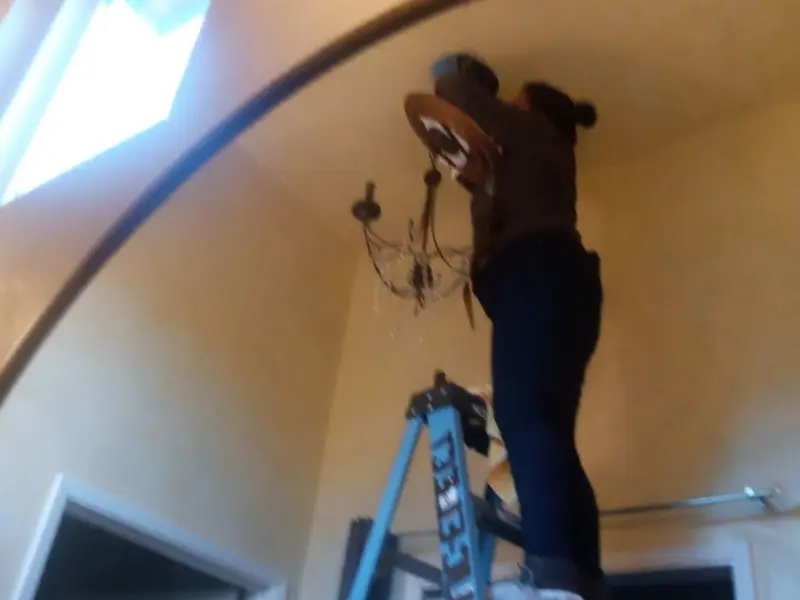 Electrician installing a chandelier in a Welch residence